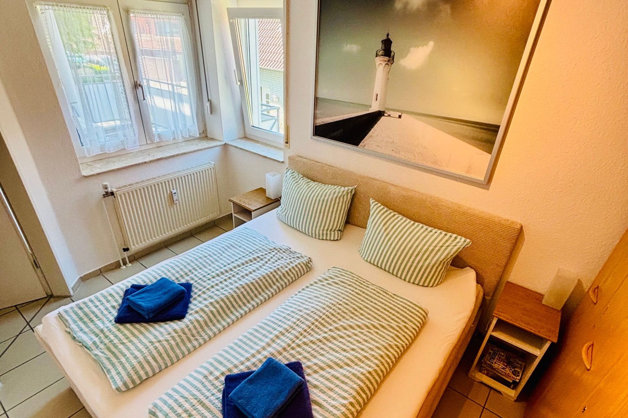 Wohnung 4 Wohnzimmer mit rotem Sofa, zwei Stühlen, Tisch und einem bunten Wandbild.