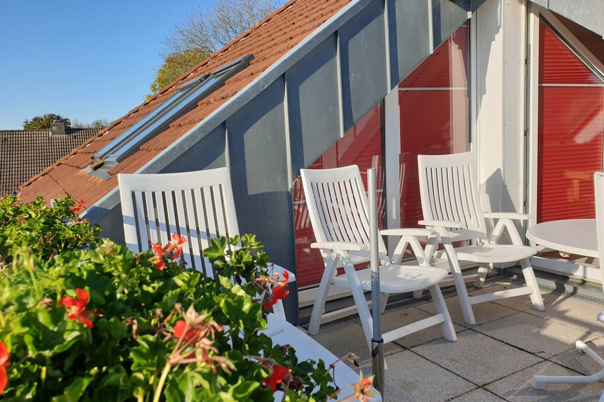 Wohnung 7 Wohnzimmer mit modernen Möbeln, Fenster mit Dachschrägen und TV auf einem Regal.